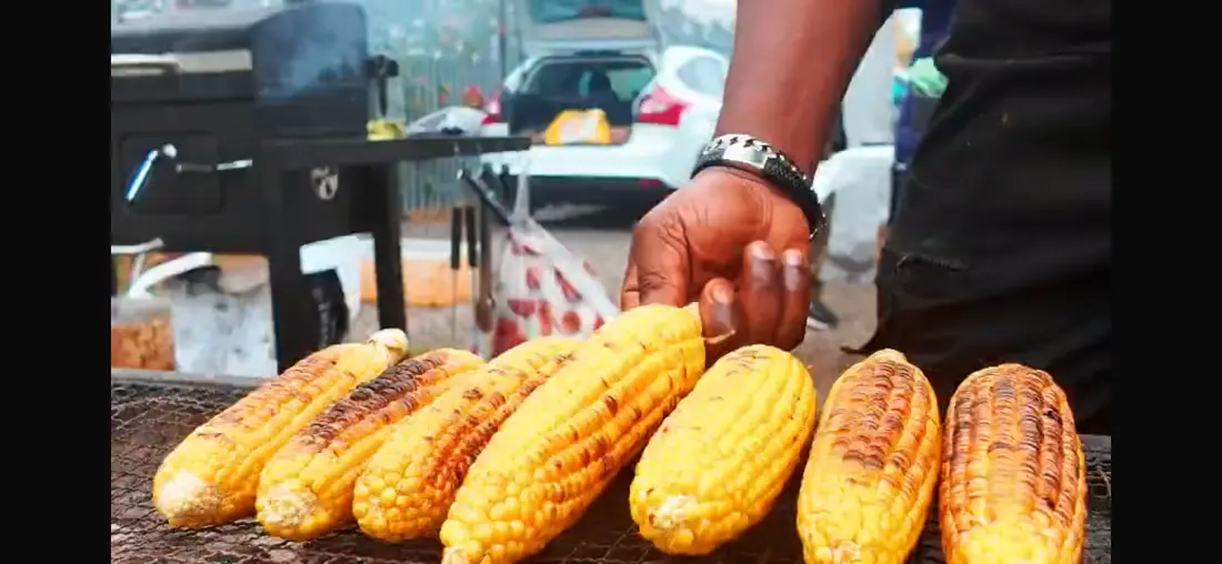 Roasted corn being handled on the grill